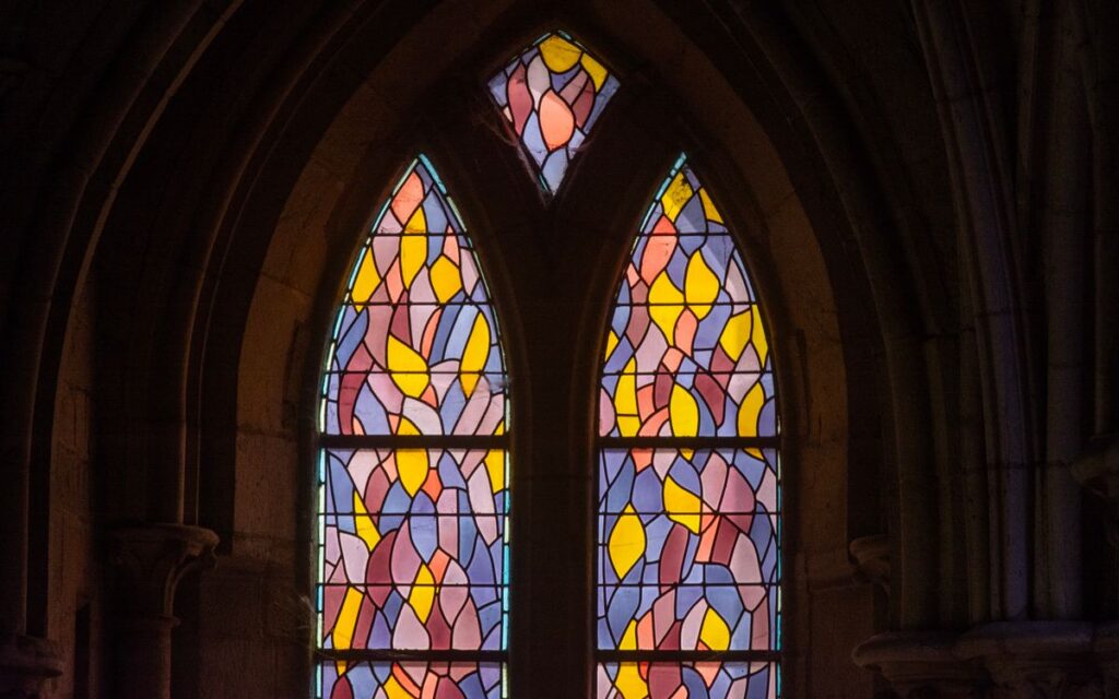 Colorful stained glass windows inside a Gothic cathedral highlighting intricate designs.