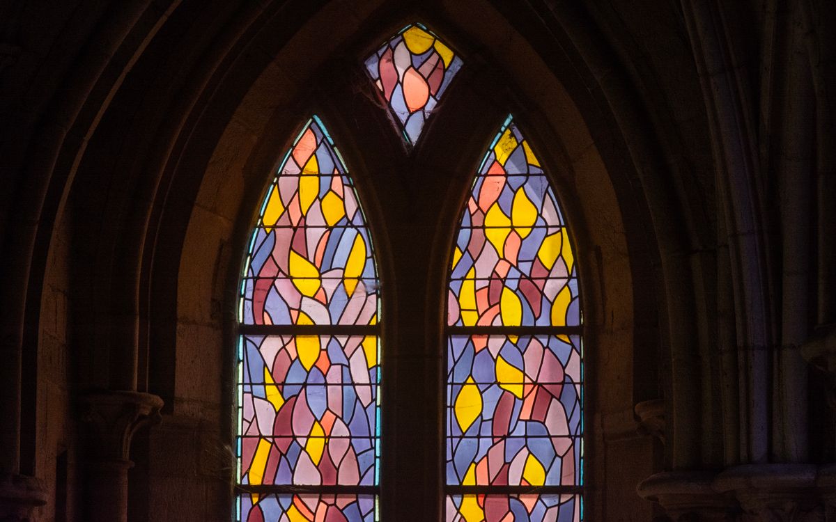 Colorful stained glass windows inside a Gothic cathedral highlighting intricate designs.