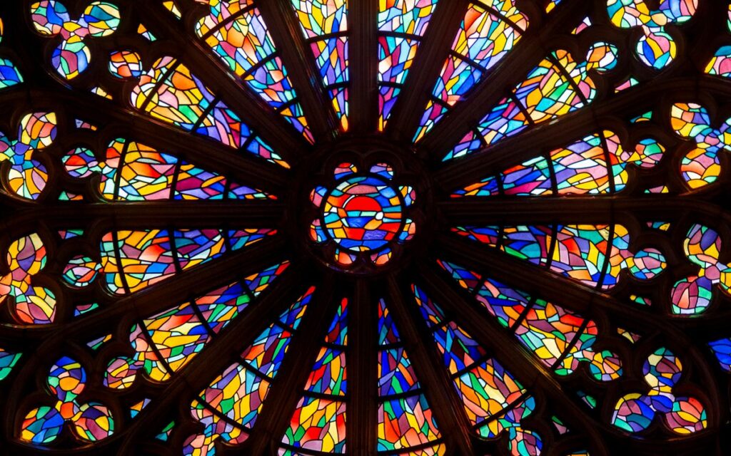 Close-up of a colorful circular stained glass window in a church, showcasing intricate patterns.