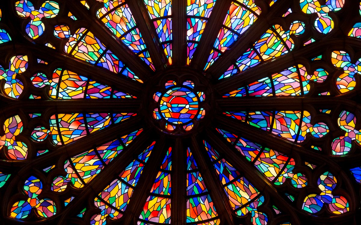 Close-up of a colorful circular stained glass window in a church, showcasing intricate patterns.