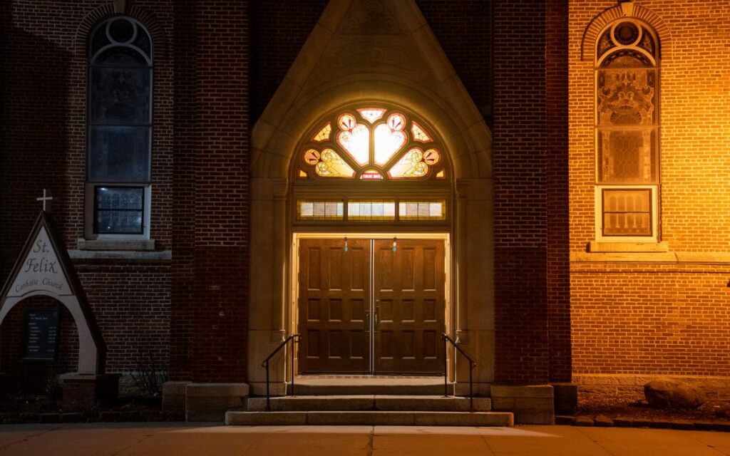 Illuminated entrance of St. Felix Catholic Church in Wabasha, MN at night.