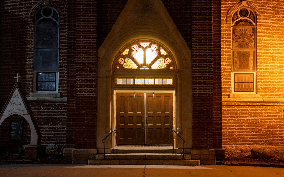 Illuminated entrance of St. Felix Catholic Church in Wabasha, MN at night.