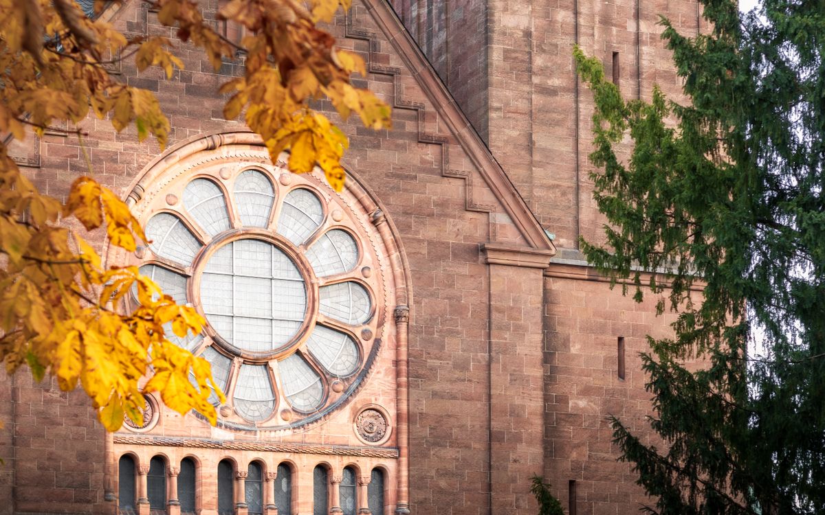 Beautiful church facade with a classic stained glass rose window, framed by autumn leaves.
