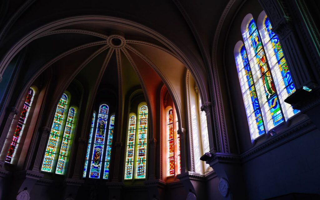 Vibrant stained glass windows in a gothic cathedral interior, capturing colorful light.