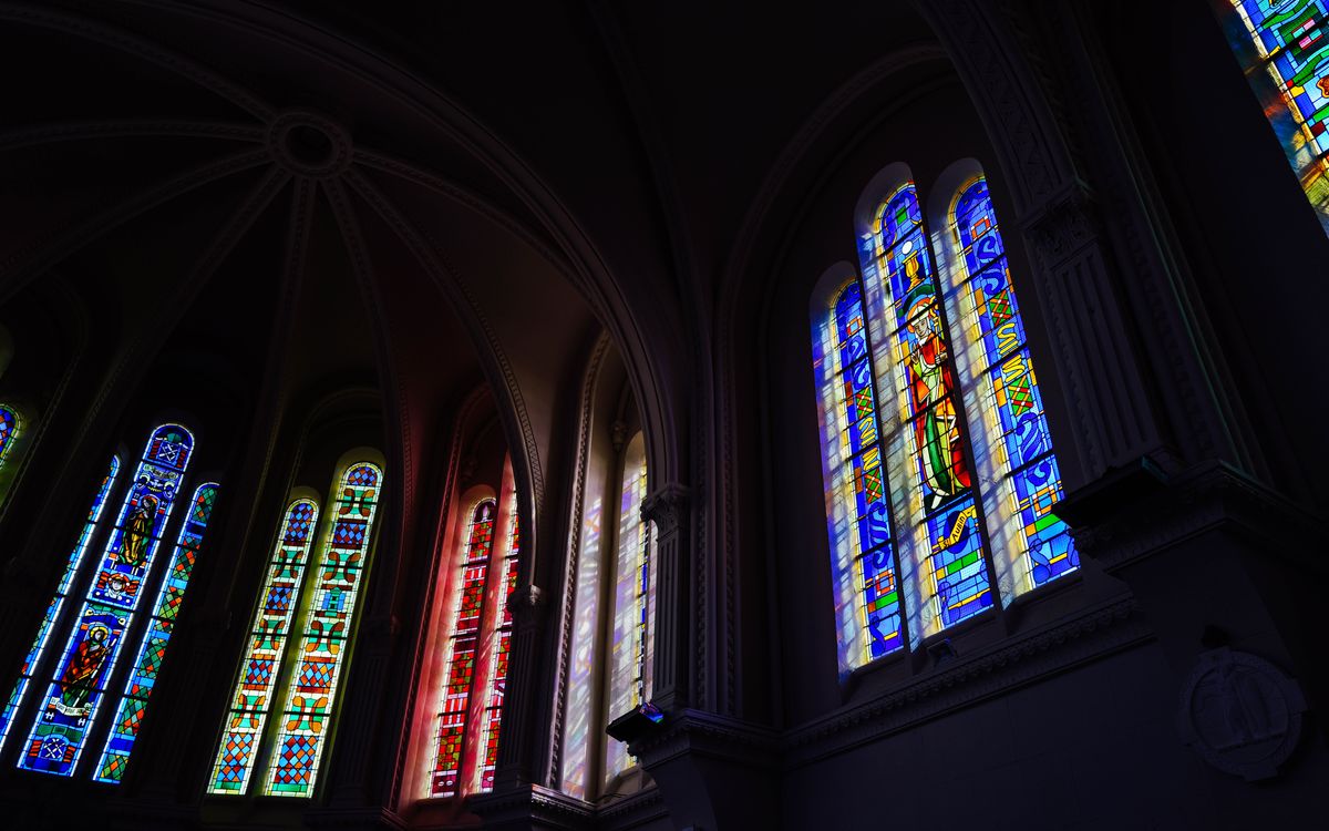 Vibrant stained glass windows inside a cathedral showcasing intricate religious art.