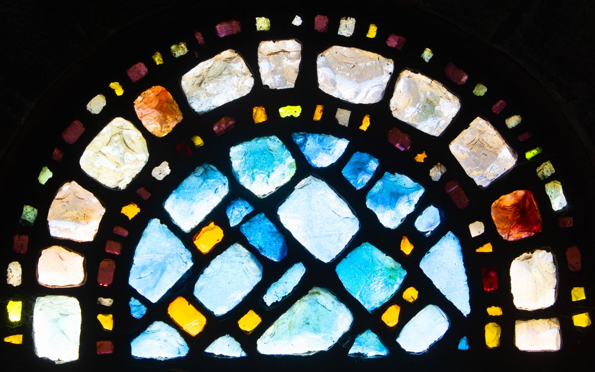 Vibrant close-up of colorful stained glass window pieces forming an abstract arch.