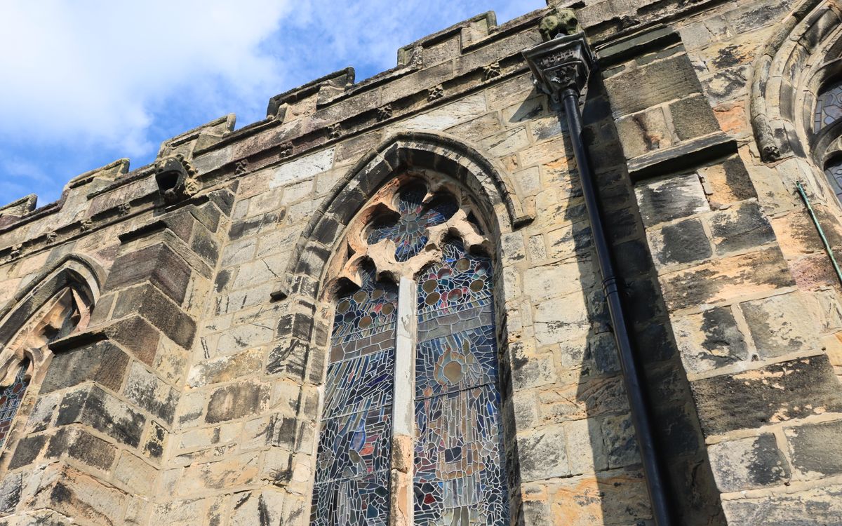 Close-up of a historic Gothic church facade with ornate stained glass windows in England.