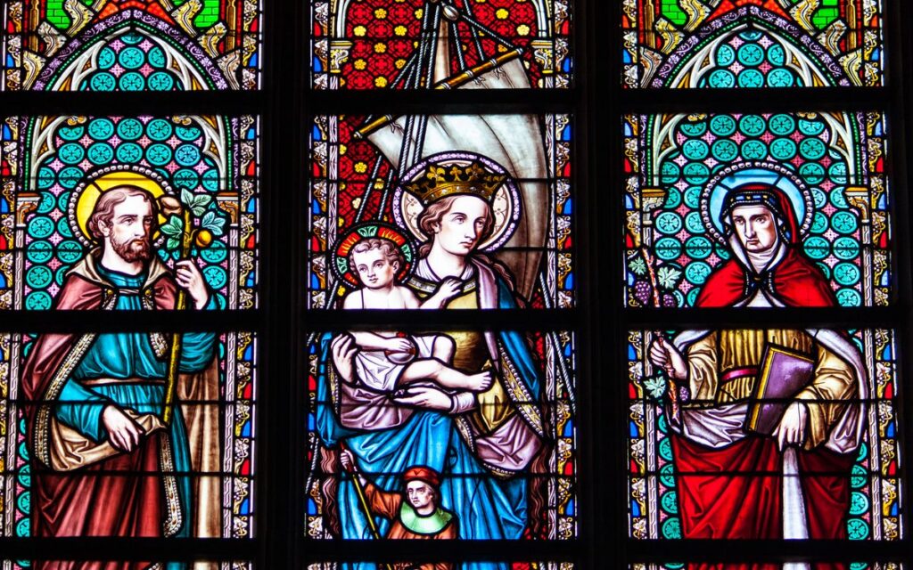 Colorful stained glass depicting saints and religious figures in a Brussels cathedral.