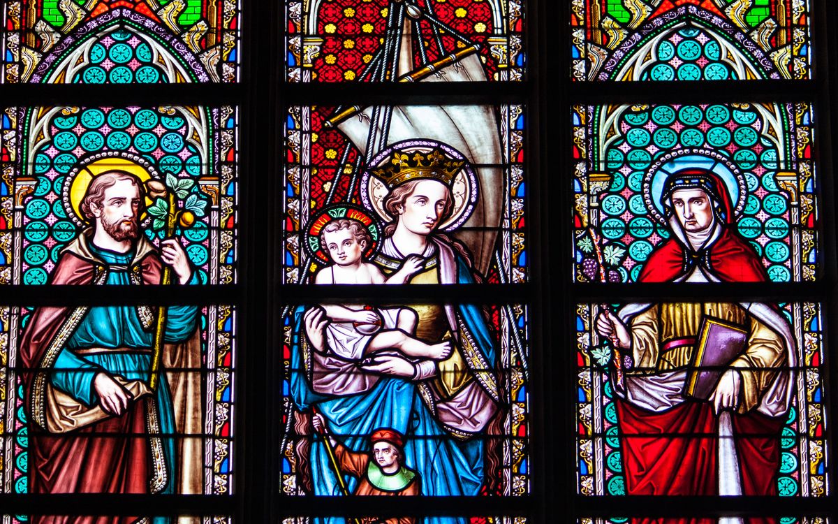 Colorful stained glass depicting saints and religious figures in a Brussels cathedral.