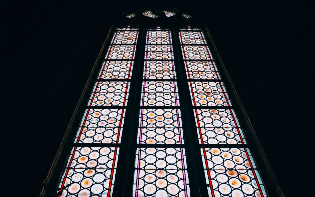 A magnificently detailed stained glass window featuring an intricate circular pattern, captured from below.