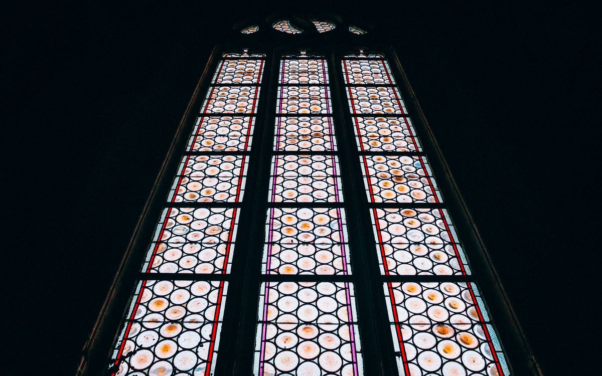 A magnificently detailed stained glass window featuring an intricate circular pattern, captured from below.