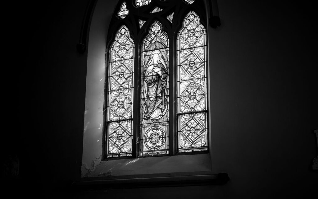 Elegant black and white photo of a religious stained glass window in a cathedral.