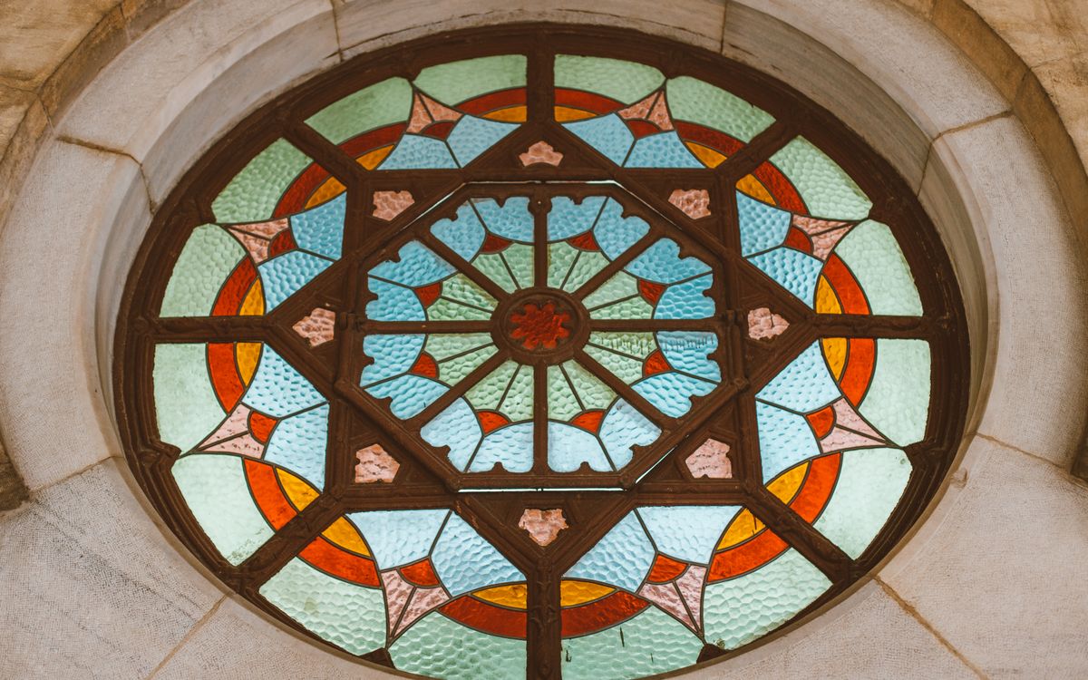 Intricate circular stained glass window featuring vibrant geometric patterns and vivid colors.