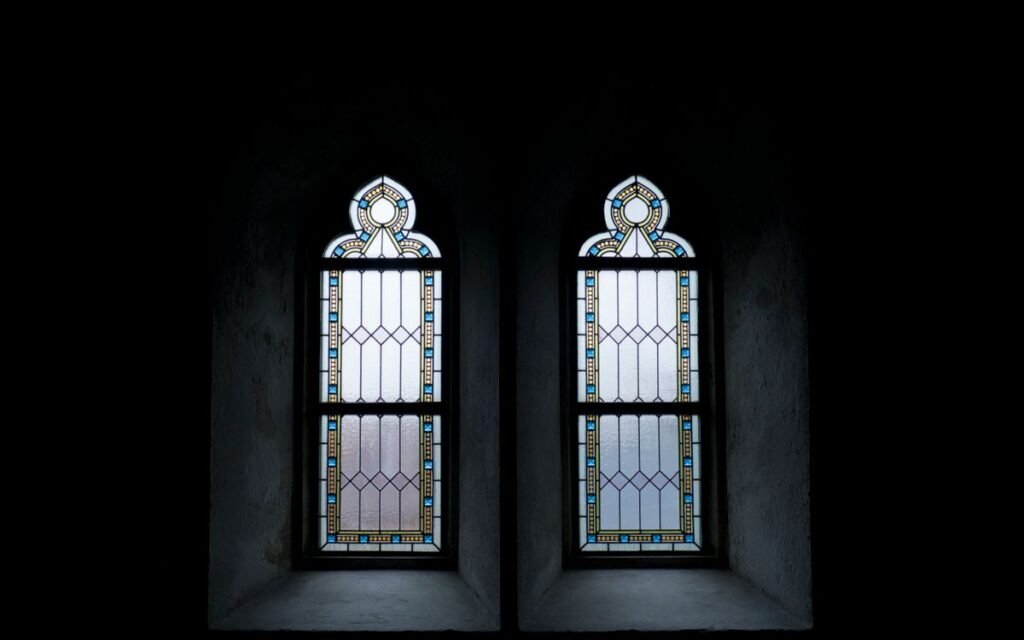Gothic stained glass windows with intricate patterns, creating a serene, minimalist atmosphere.