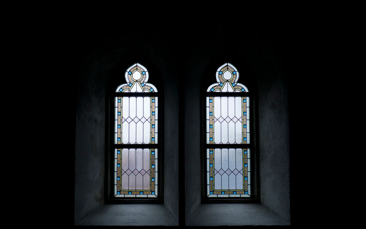 Gothic stained glass windows with intricate patterns, creating a serene, minimalist atmosphere.