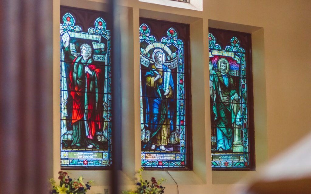 Colorful stained glass windows depicting religious figures in a church setting.