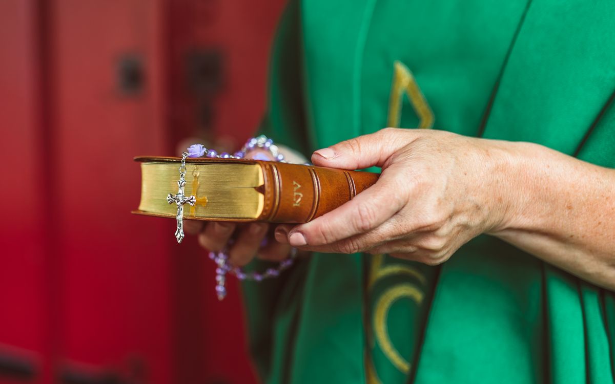 A close-up image of hands holding a Bible with a rosary, symbolizing faith and devotion.