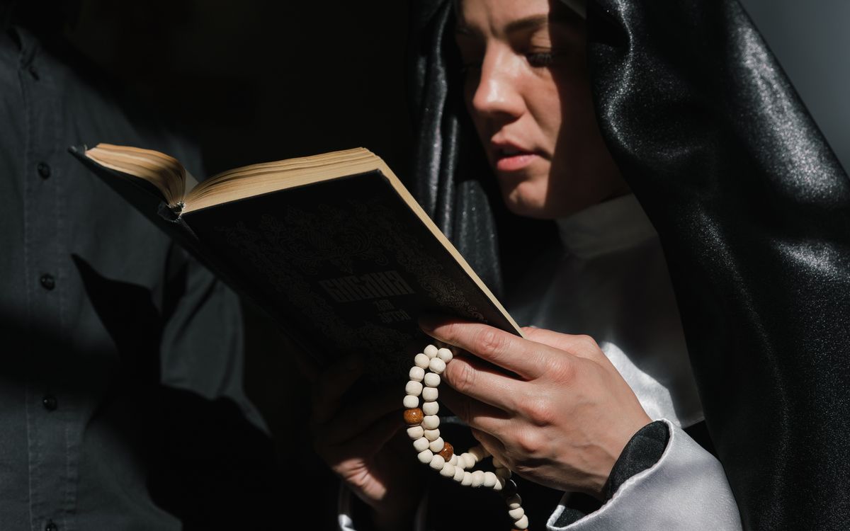 A nun intensely reading a book while holding a rosary, symbolizing devotion.