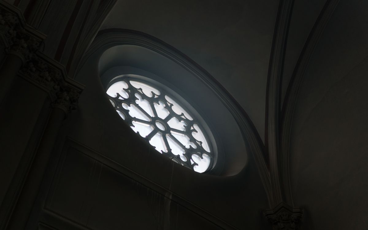Low-angle view of a Gothic cathedral window showcasing intricate design and natural light.