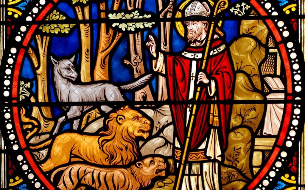 Vibrant stained glass window showcasing a saint with animals in a church setting.